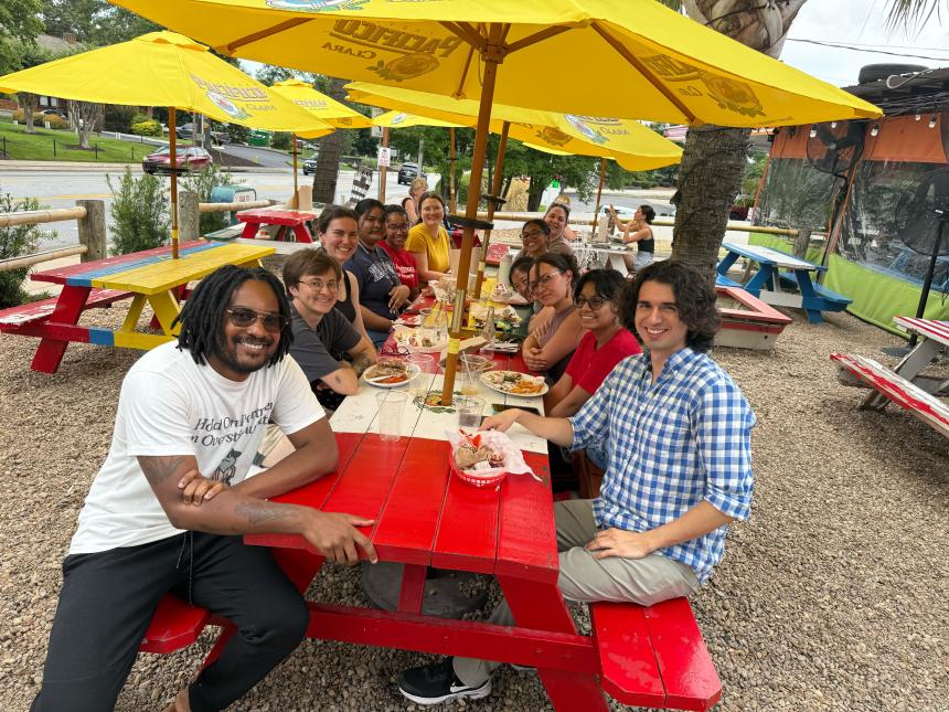 A group of 12 people at picnic tables in front of Cali n Titos